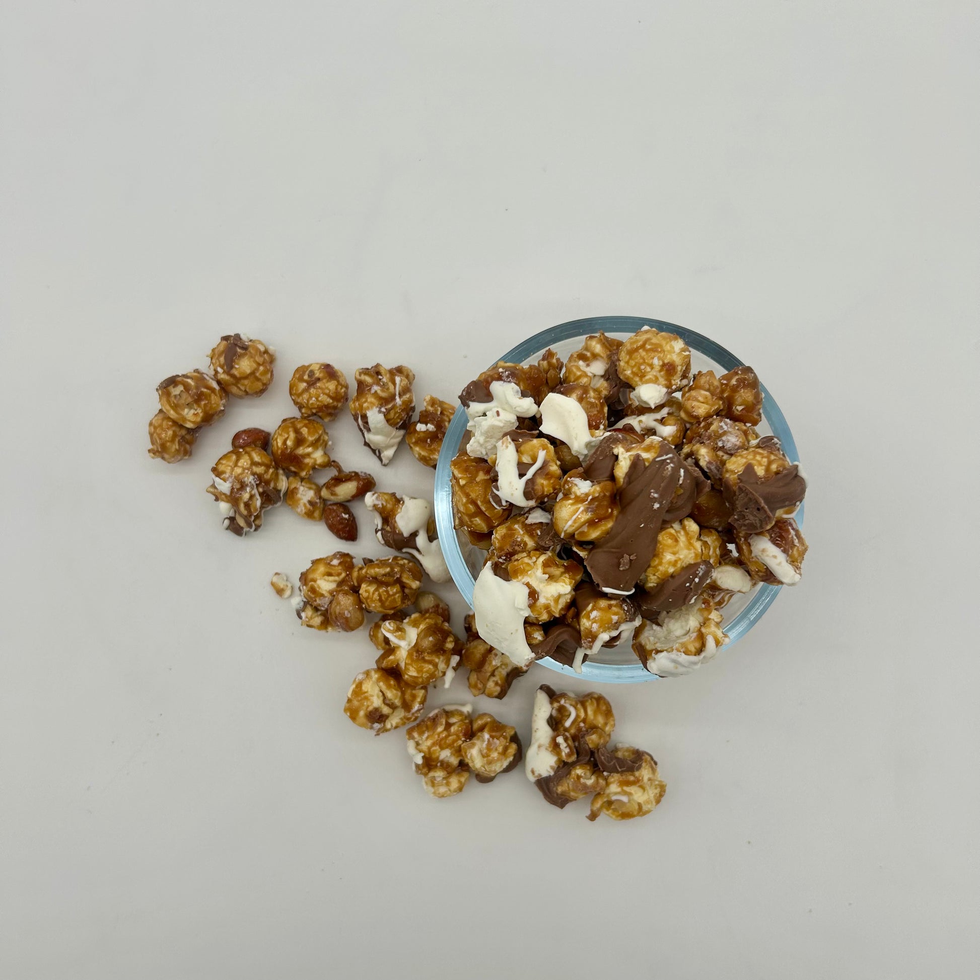 Homemade Caramel corn and roasted Spanish peanuts drizzled with milk and white chocolate. 